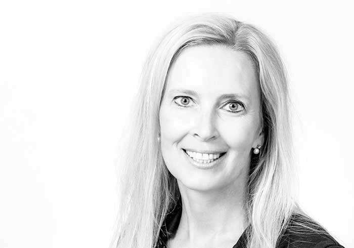 Lächelnde Frau mit langen hellen Haaren blickt in die Kamera.
