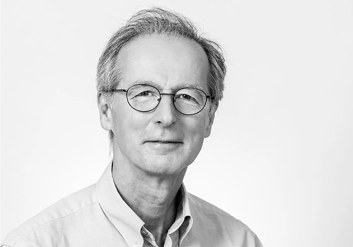Er hat glatte, kurze Haare und trägt eine Brille.