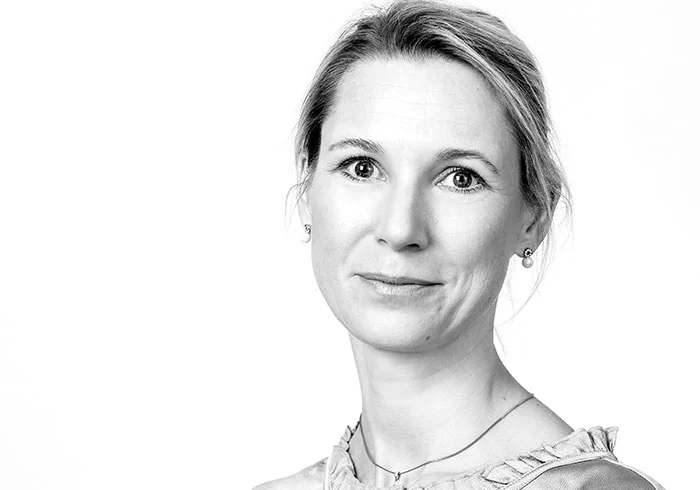 Sie hat ihre Haare hinten zusammengebunden und lächelt freundlich in die Kamera.