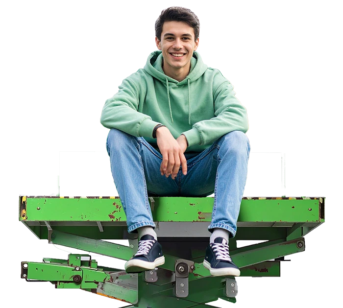 Junger Mann im grünen Hoodie sitzt lächelnd auf einer grünen Hebebühne 